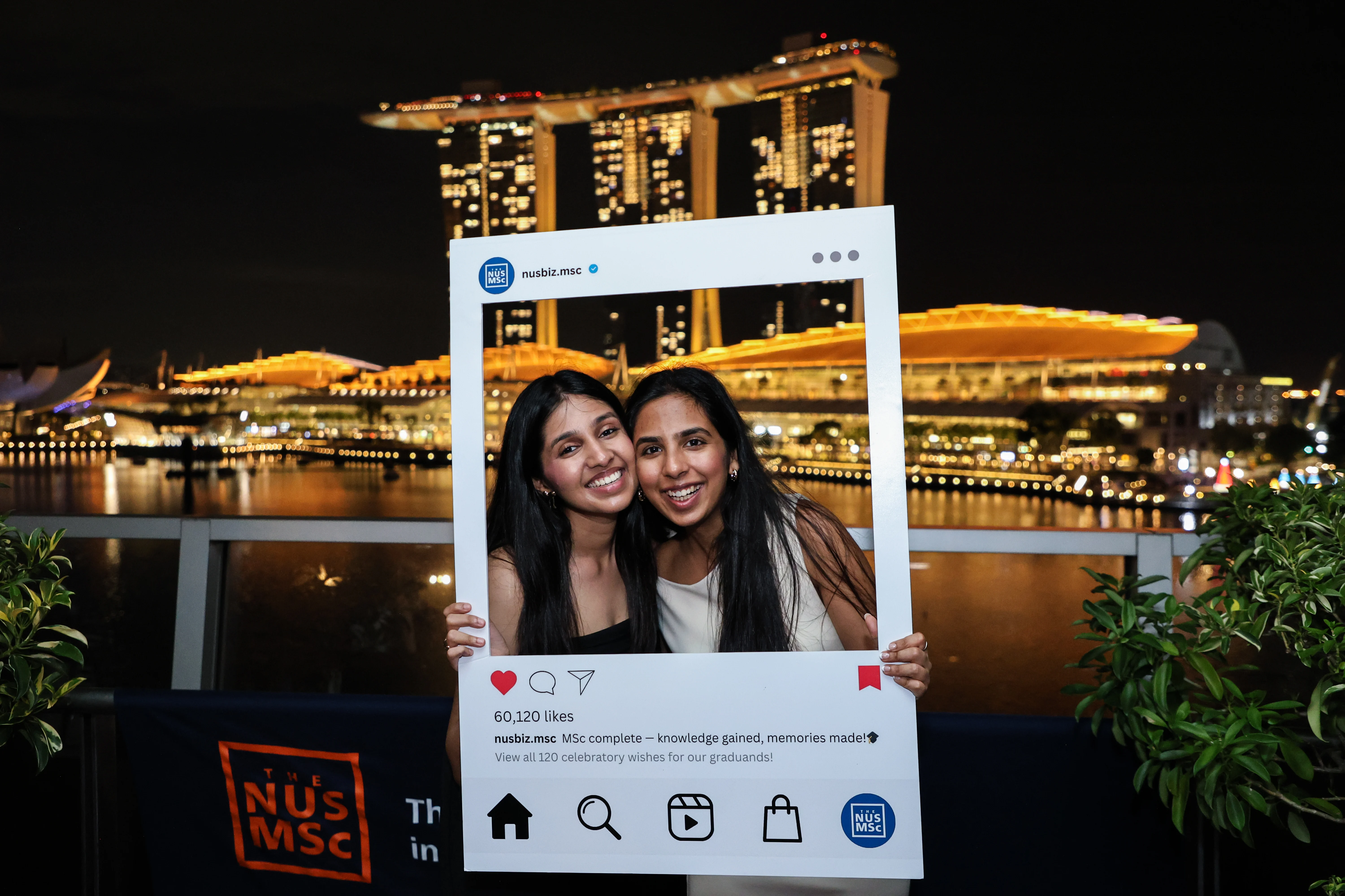 Graduates posing with oversized social media prop frame at Singapore venue