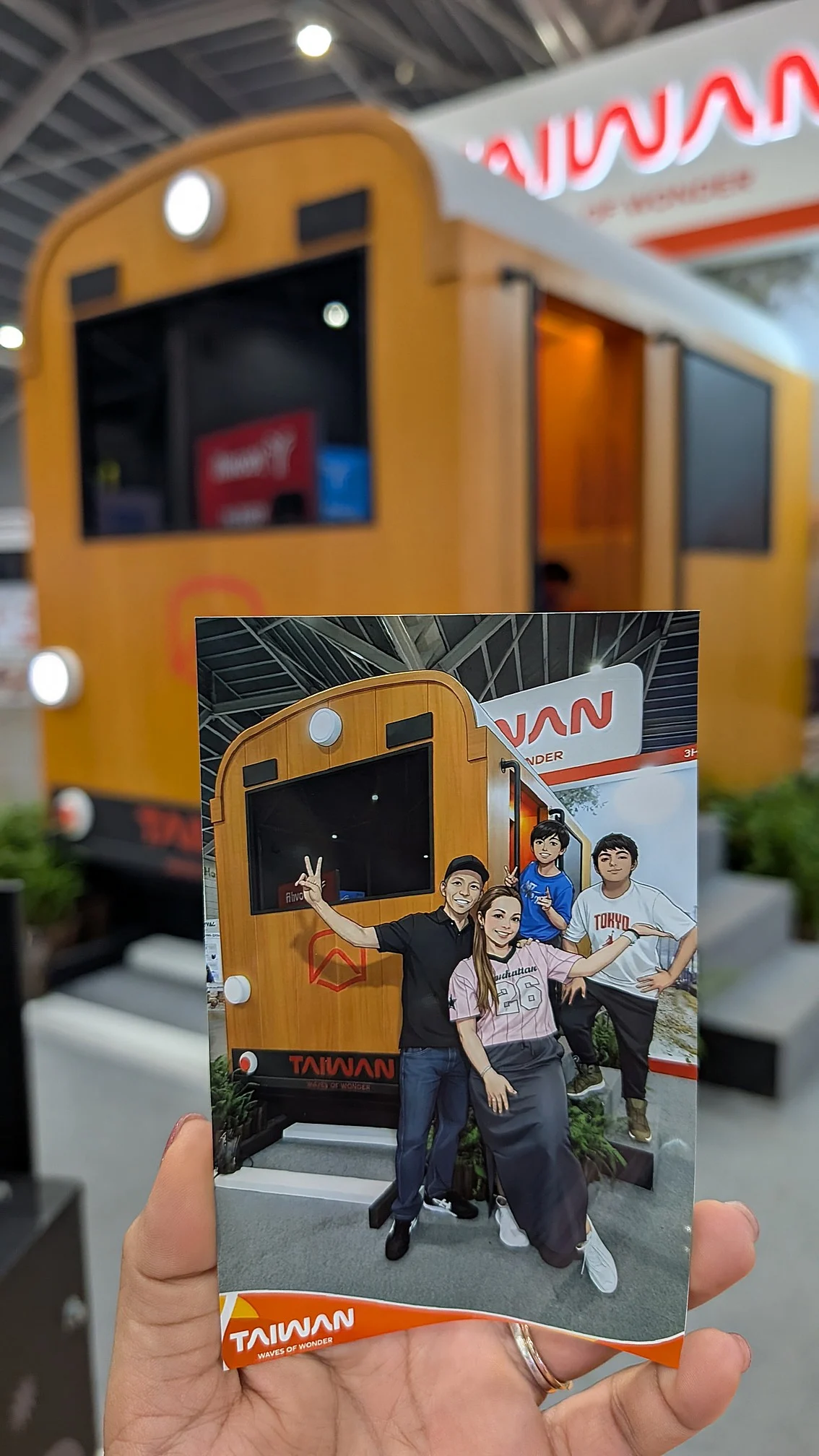 A hand holding a customized printout in front of an event backdrop booth setup