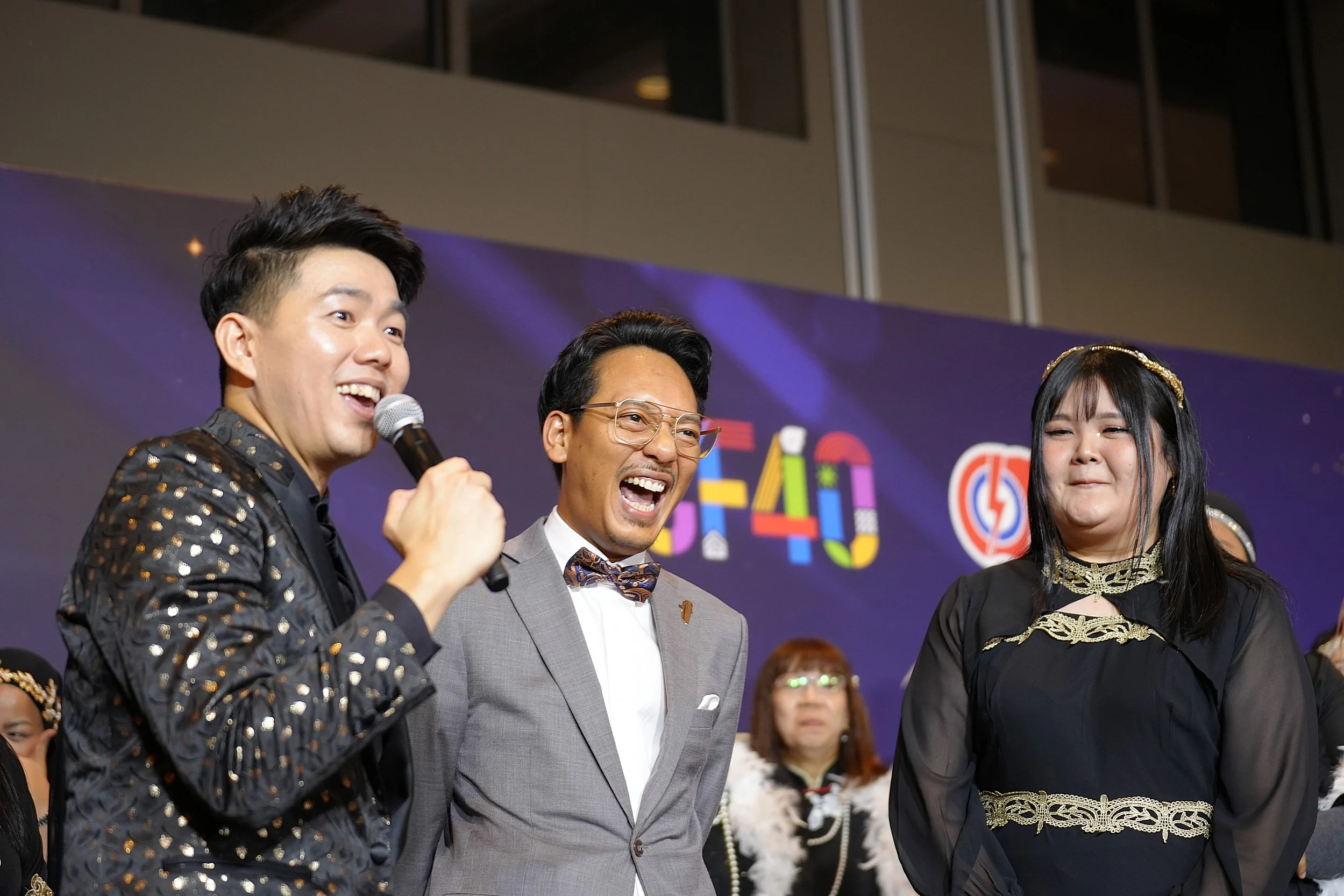 Stage emcee interacting closely with smiling guests during an award ceremony