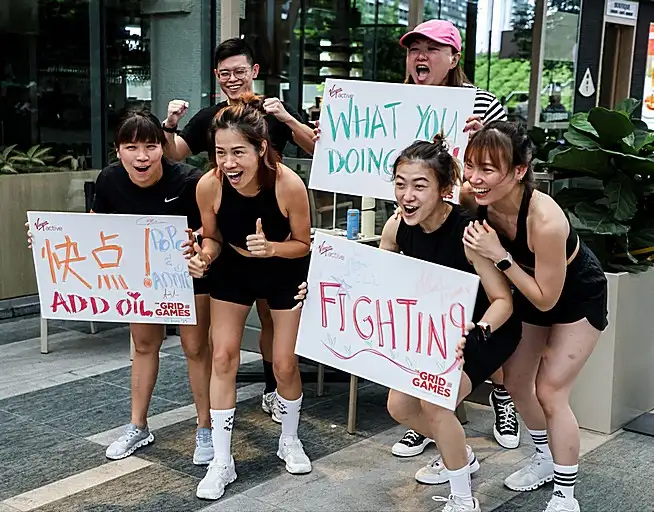 Group of event participants holding up cheering signs and posing together outdoors