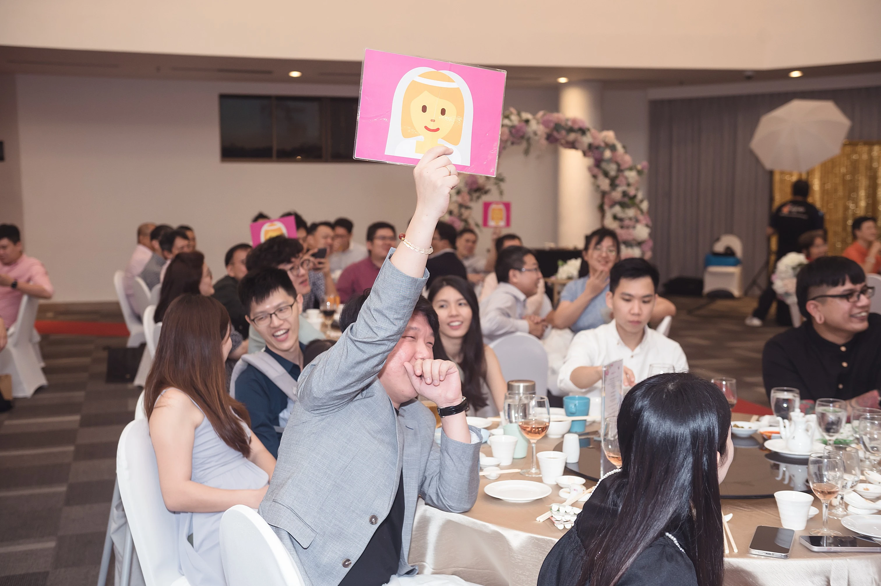 Wedding guest raising a vote sign during an interactive banquet table game