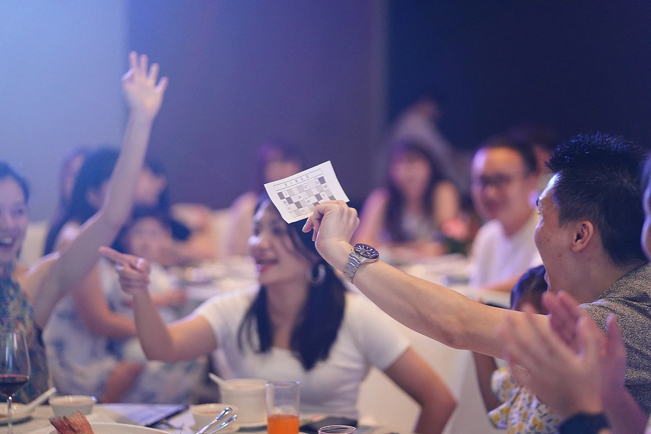 Wedding guests excitedly holding up bingo cards during a reception table challenge