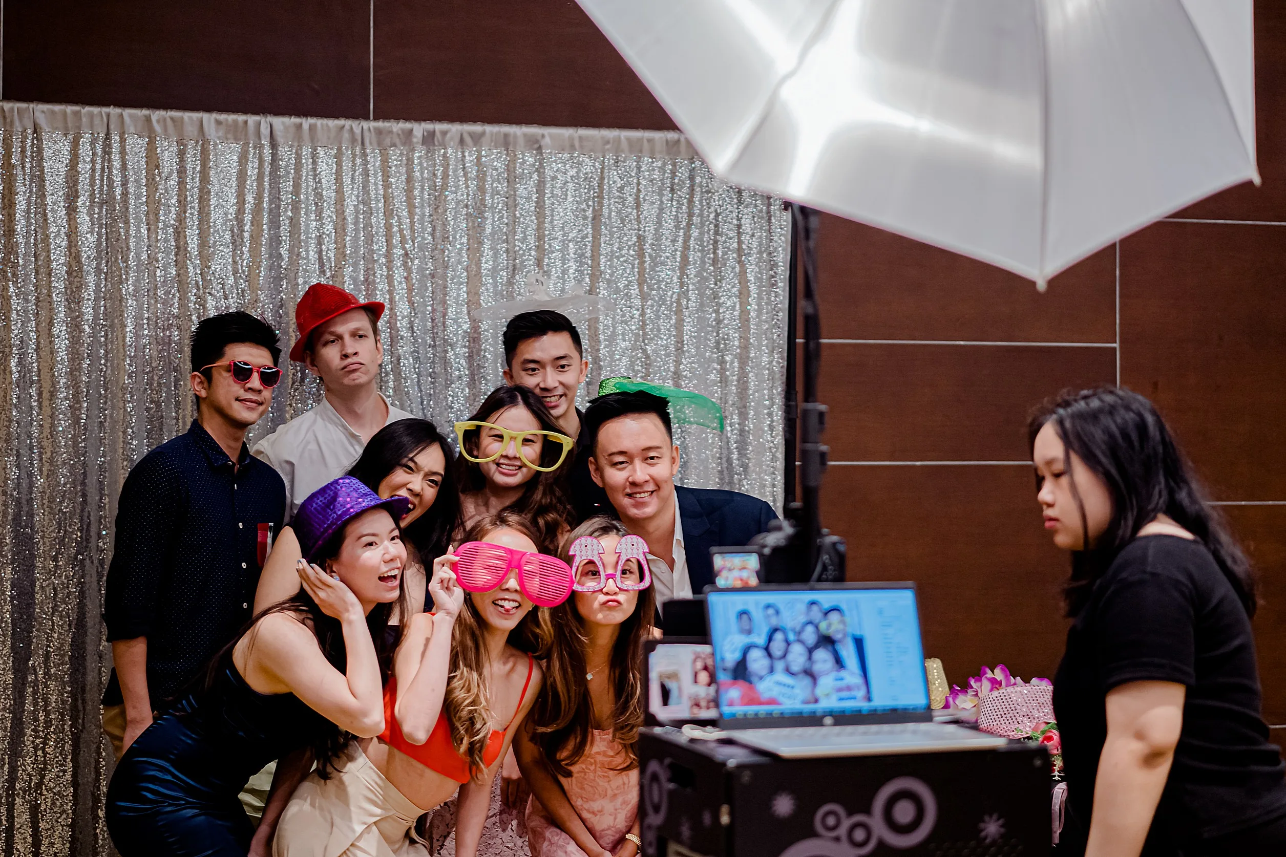 Group of wedding guests wearing funny props and posing in front of a photo booth camera